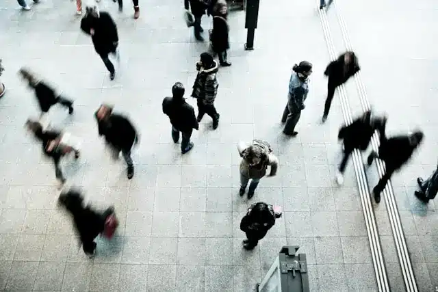 Mensen lopen door een drukke, open ruimte met een grijze vloer.