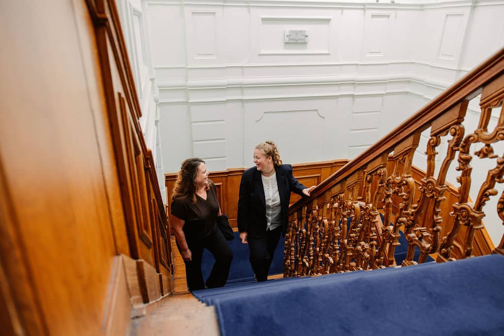 twee vrouwen die de trap op lopen terwijl ze naar elkaar lachen.
