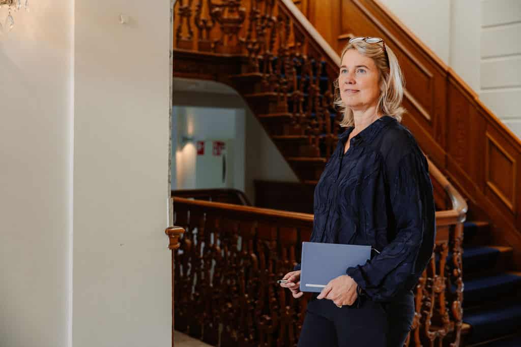 Mevrouw met pen en schrift in haar handen.